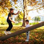 Copii de vârste diferite care se joacă împreună într-un parc, printre frunze de toamnă