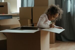 Copil care construiește un robot din cutii de carton și tuburi, pictându-l cu pensula